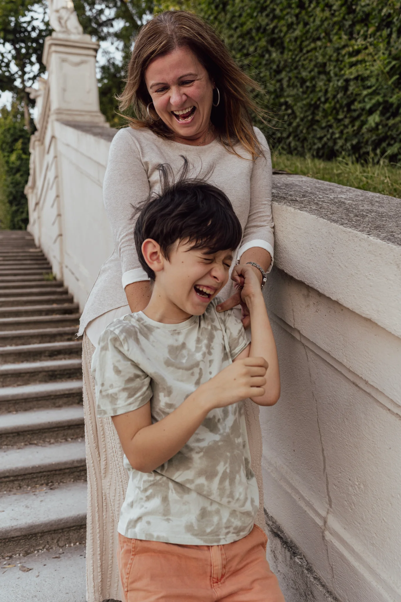 Mother and son standing on the steps at the Belvedere Gardens, smiling together.