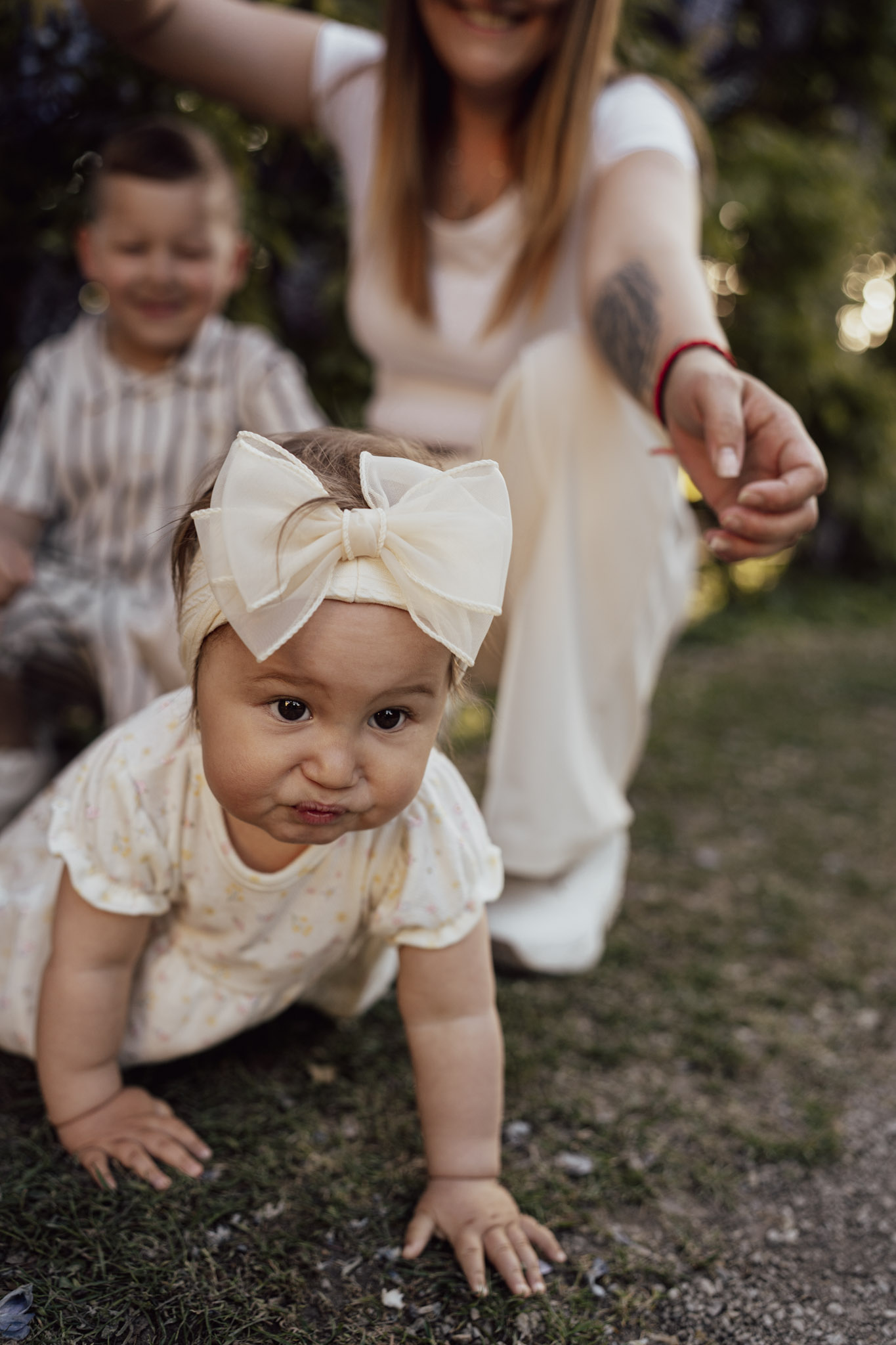 Mother sitting on the ground with her children while her little daughter explores the world around her.