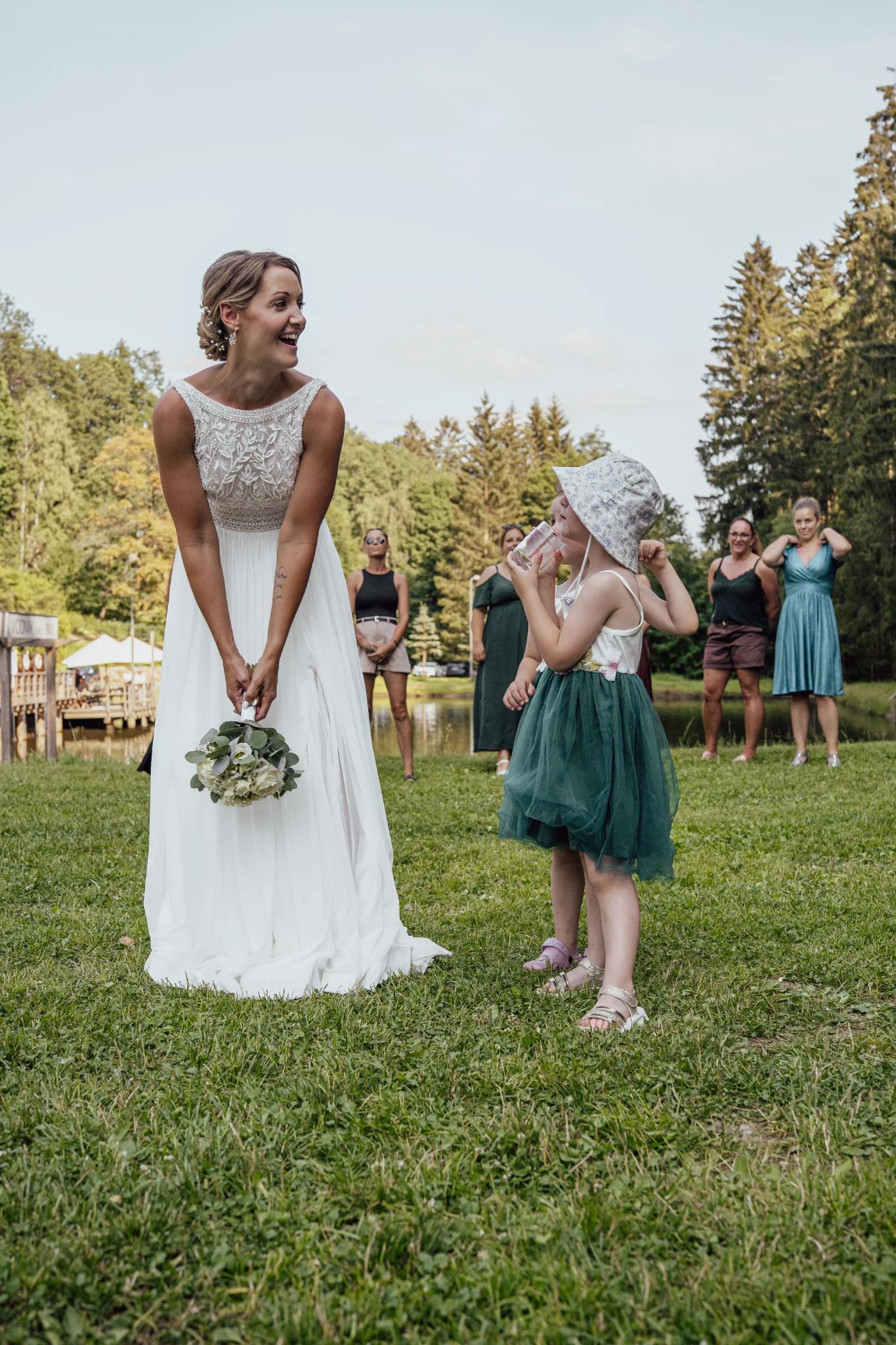 Bride tossing her wedding bouquet while her two little daughters stand beside her.