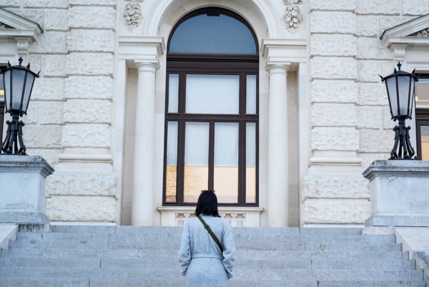 Woman walking up the steps towards the Hofburg, photographed from behind.