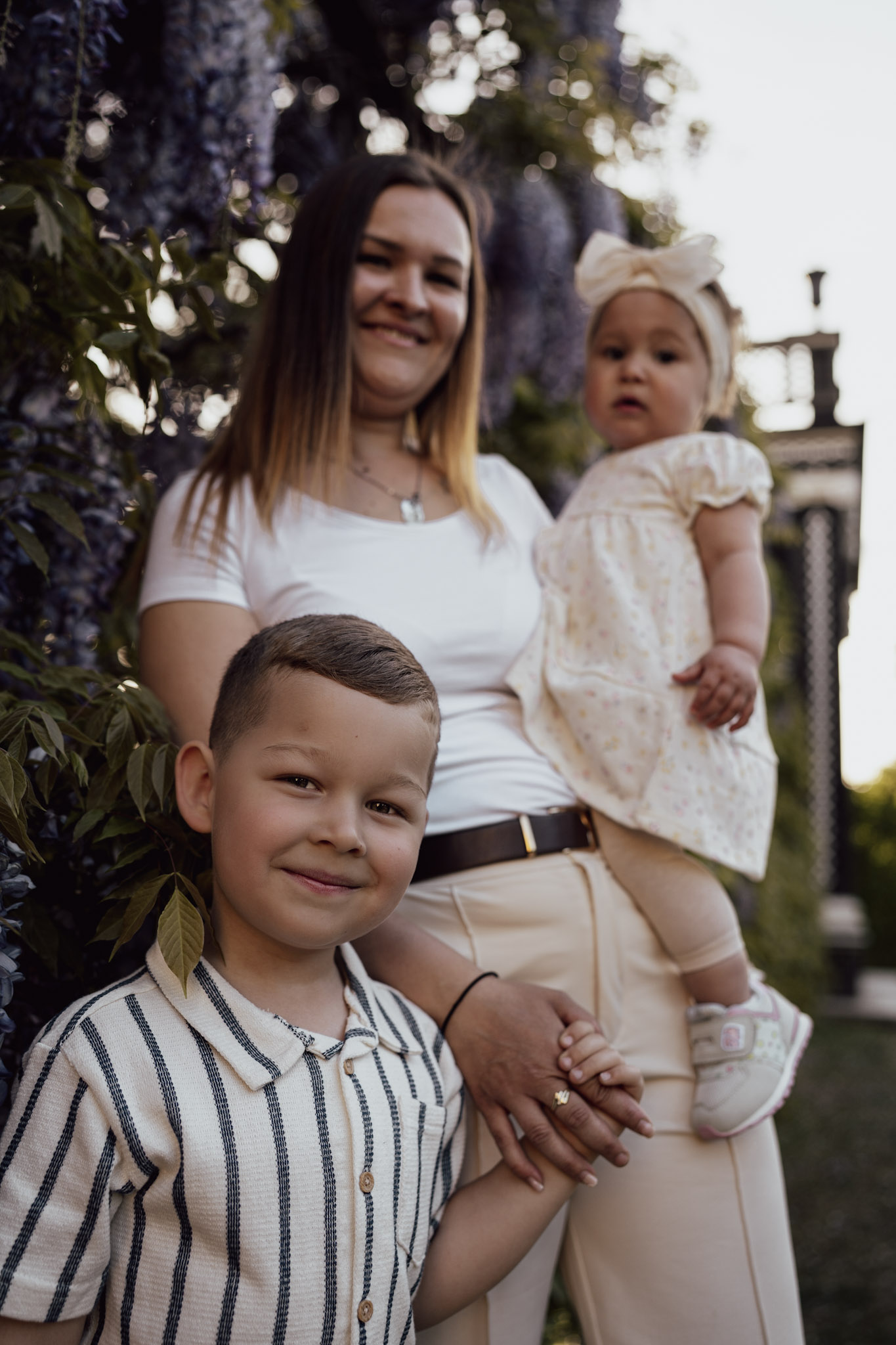 Mother holding both children, her daughter in her arms and her son by the hand.