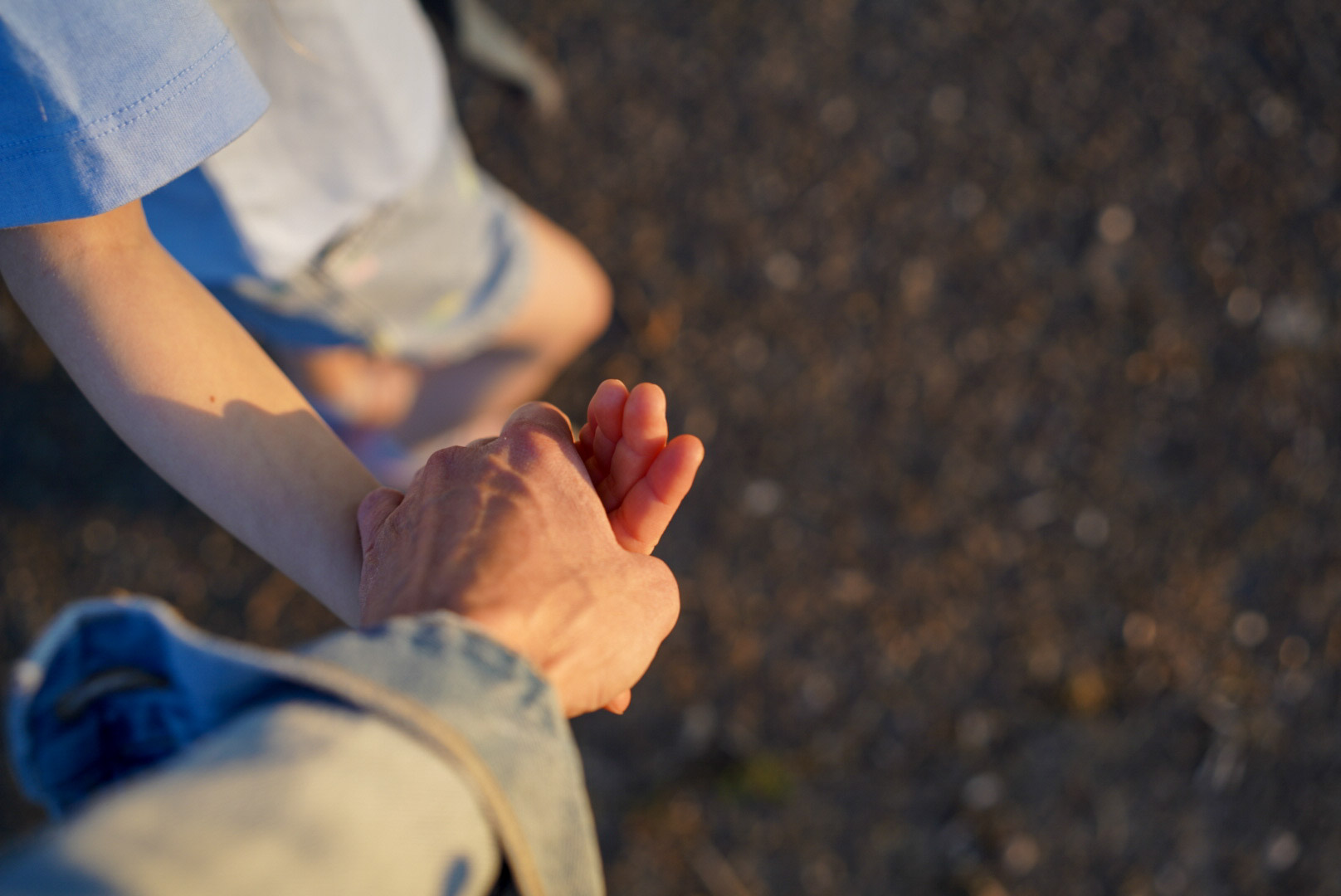Close-up of a mother and daughter's intertwined hands.